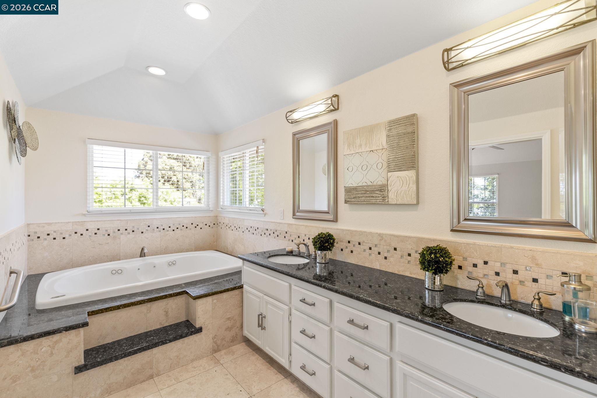 1267 Quiet Circle Concord, CA 94521 - Photo 34 of 72 a bathroom with double vanity sinks a mirror and a bathtub next to a window