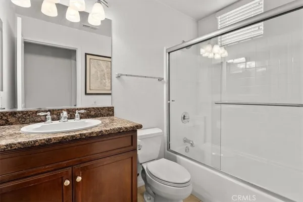 a bathroom with a granite countertop sink toilet mirror and shower