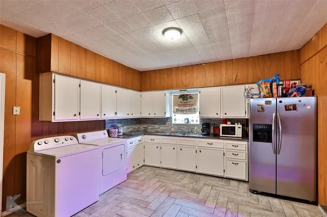 a kitchen with stainless steel appliances a sink a stove a refrigerator cabinets and a window