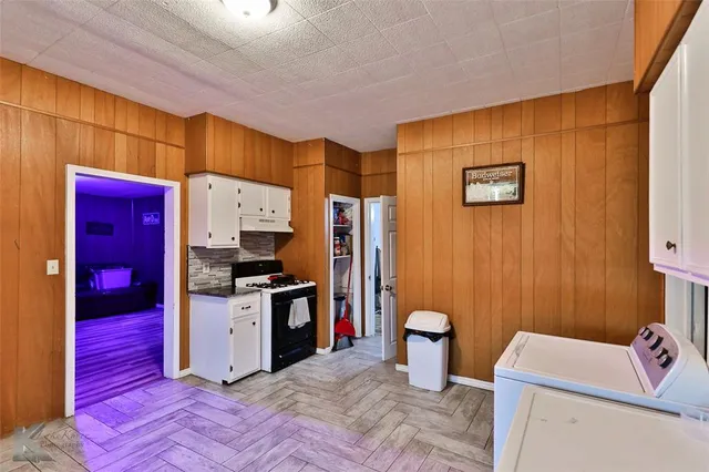 a kitchen that has a sink and a stove with wooden floor