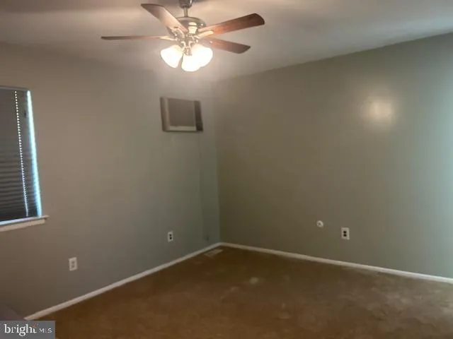 an empty room with a window and a fan