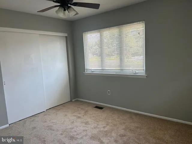 an empty room with a window and a fan