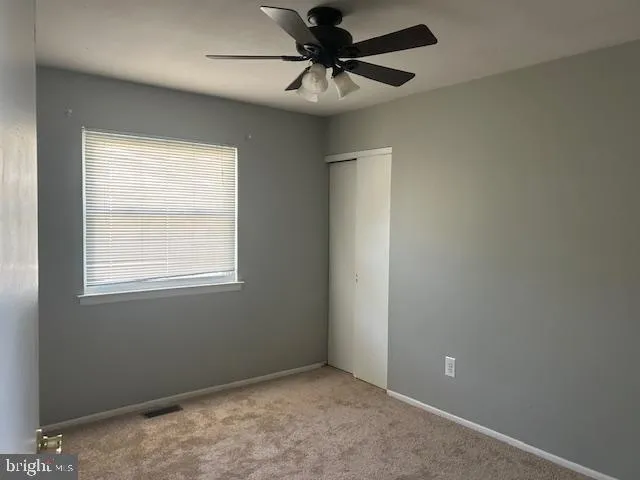 an empty room with a window and a fan