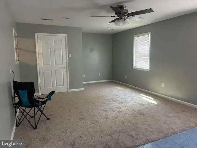 an empty room with windows and fan