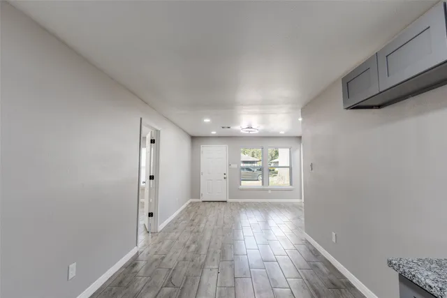 a view of an empty room with wooden floor and window