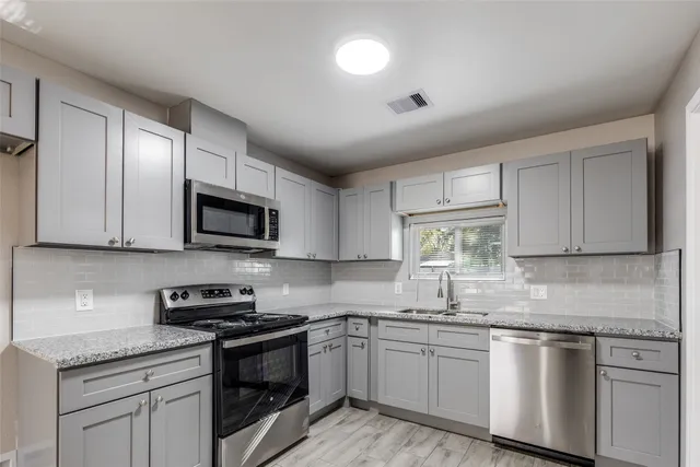 a kitchen with stainless steel appliances granite countertop white cabinets granite counter tops and a hard wood floors