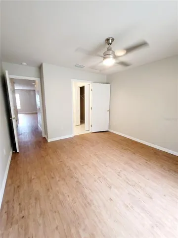 a view of an empty room with a chandelier fan and a window