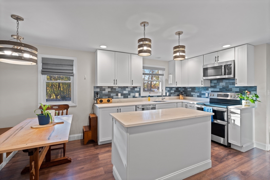 2 Woodbrier Road Topsfield, MA 01983 - Photo 2 of 29 a kitchen with a sink dishwasher a stove a microwave oven and a dining table with wooden floor