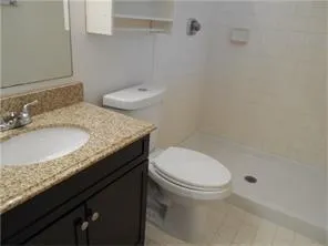 a bathroom with a granite countertop sink a toilet and a mirror