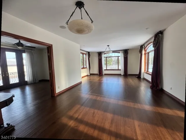 a view of an empty room with window and wooden floor