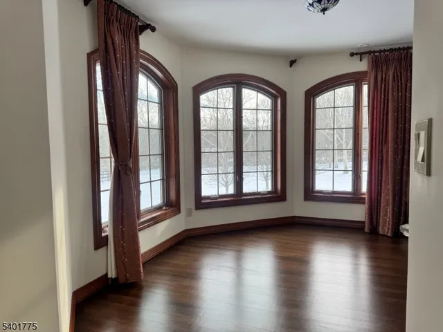 an empty room with wooden floor and windows with curtains