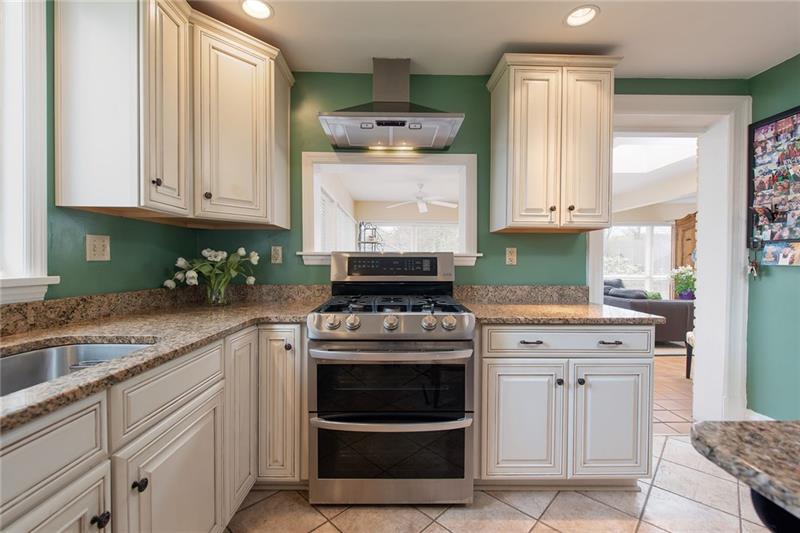 304 Quaker Road Sewickley, PA 15143 - Photo 9 of 25 A gas double oven and range hood with passthrough to the living room are a focal point of the kitchen.