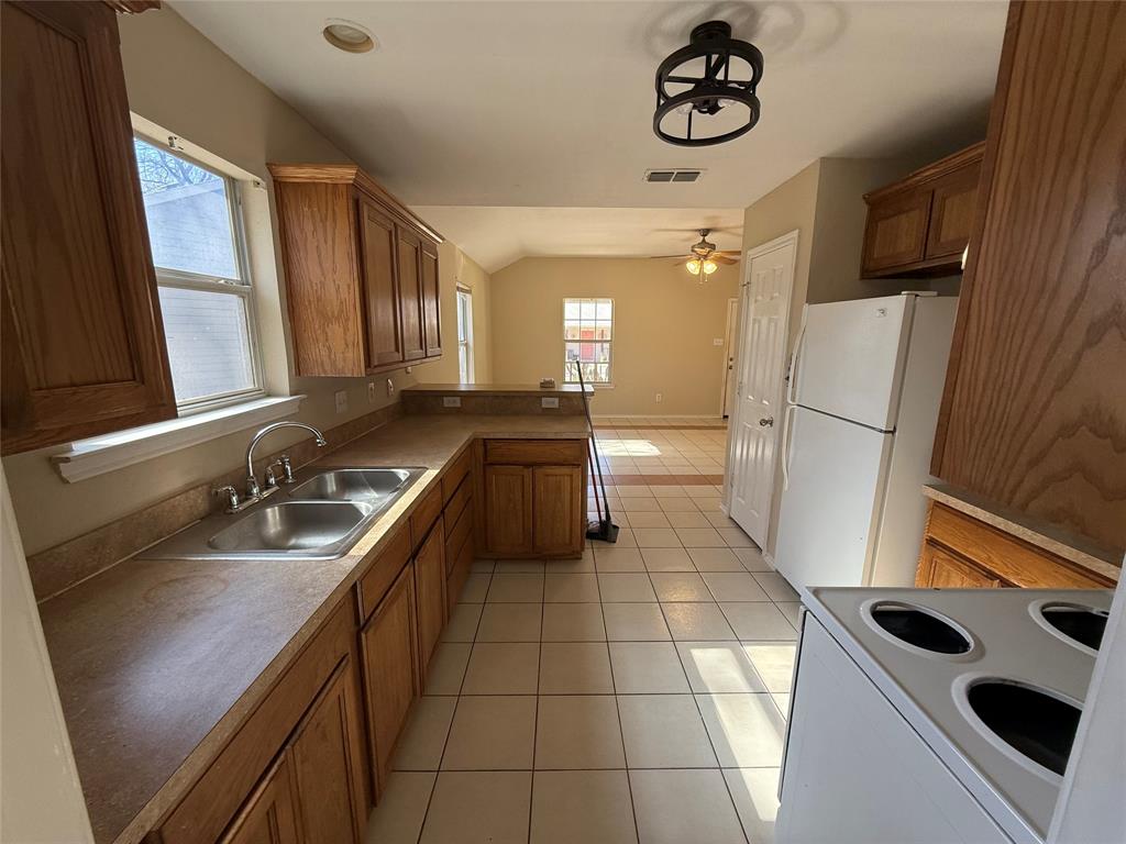 900 Reese Lane Azle, TX 76020 - Photo 9 of 15 a kitchen with a sink a refrigerator and cabinets