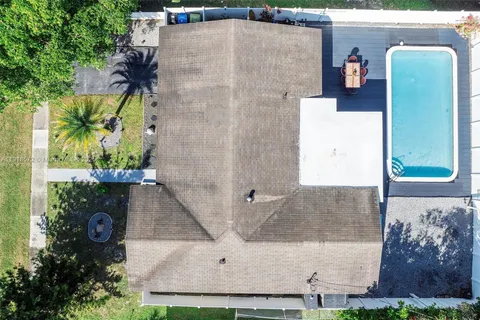 an aerial view of a house with a yard and large tree