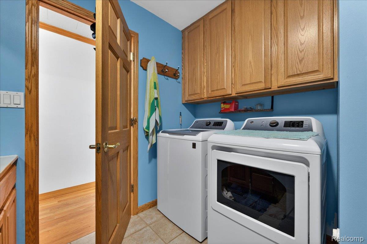 4049 Slattery Road North Branch, MI 48461 - Photo 23 of 45 Laundry room with cabinet space, washer and clothes dryer, and light tile patterned floors