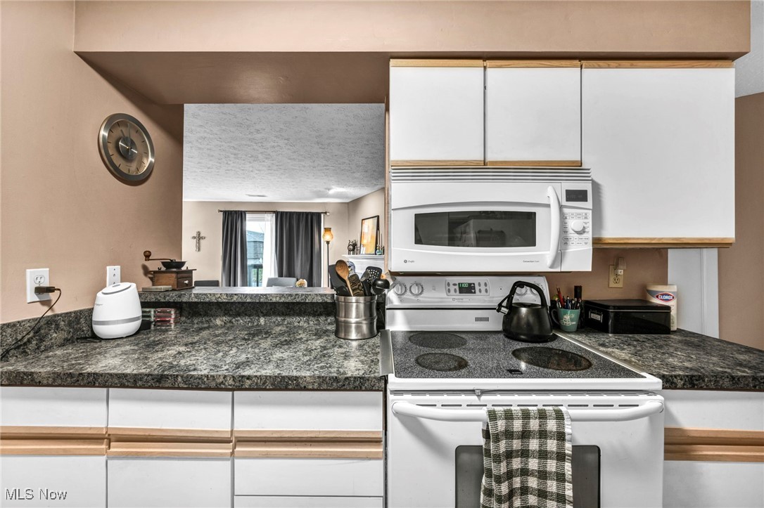 4750 Oak Point Road, Unit 304 Lorain, OH 44053 - Photo 12 of 29 Kitchen with white appliances, white cabinets, dark countertops, and a textured ceiling