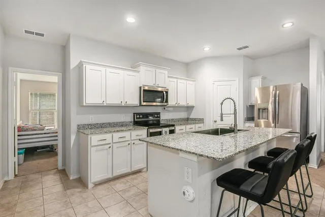 a kitchen with kitchen island granite countertop a stove top oven microwave and cabinets