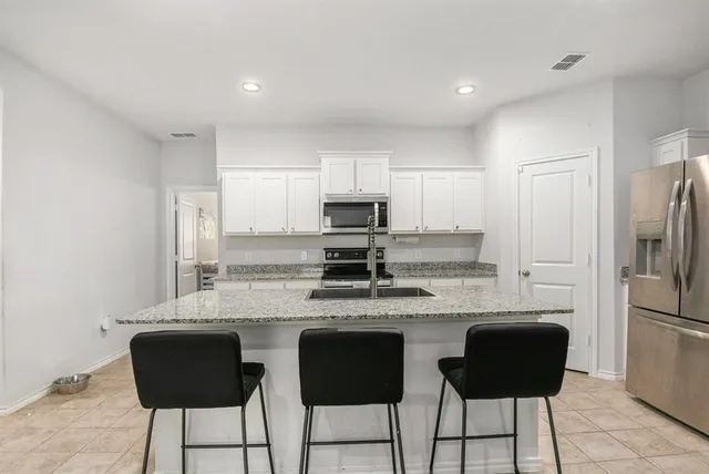 a kitchen with stainless steel appliances granite countertop a stove a refrigerator a sink a stove with white cabinets and chairs