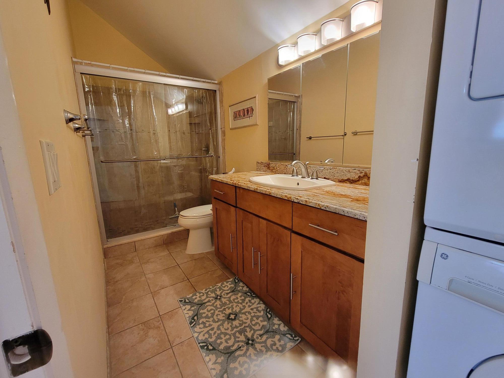 1605 Highway 1, Unit M2210 Jupiter, FL 33477 - Photo 23 of 28 a bathroom with a granite countertop sink a toilet a mirror and shower