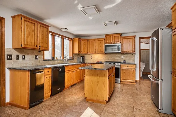 a kitchen with stainless steel appliances granite countertop a stove top oven a refrigerator a sink and dishwasher