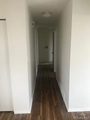 a view of a hallway with wooden floor and a bathroom