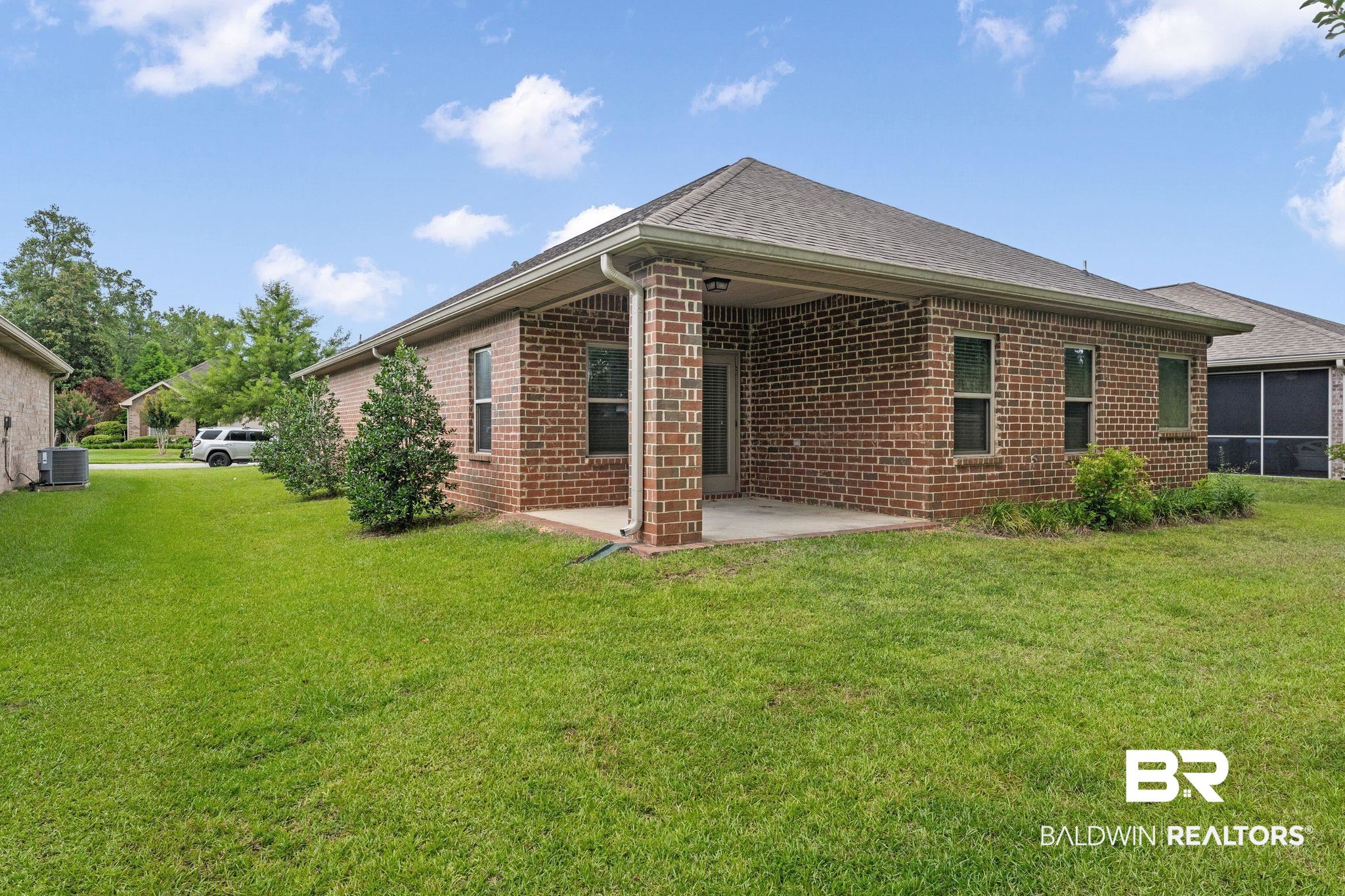 1464 Surrey Loop Foley, AL 36535 - Photo 2 of 24 Rear view of house featuring a patio, brick siding, a lawn, and a shingled roof