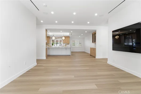 a view of an empty room with kitchen and window