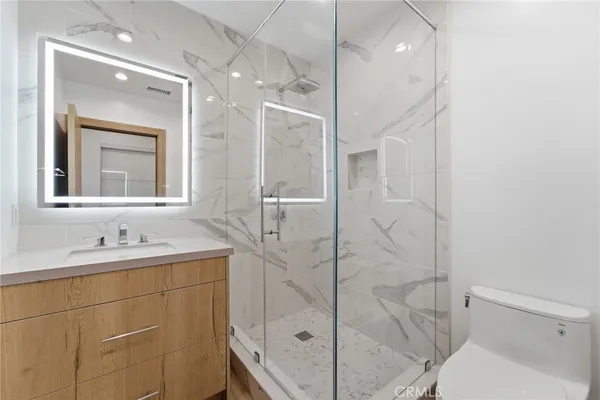 a bathroom with a shower sink vanity mirror and toilet