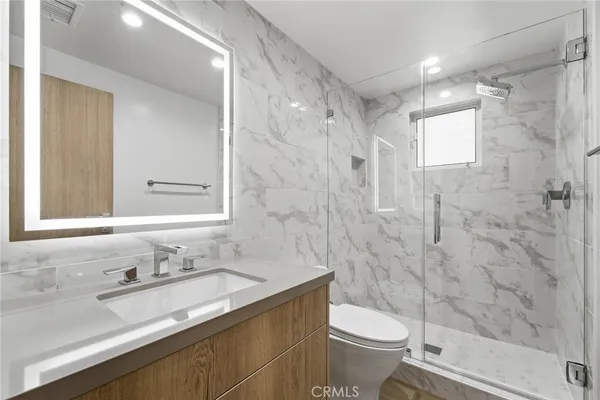 a bathroom with a granite countertop sink toilet and shower