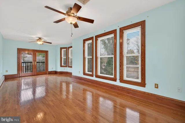 an empty room with wooden floor a ceiling fan and a ceiling fan