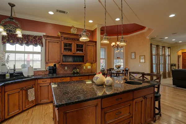 a kitchen with stainless steel appliances granite countertop a sink a stove and a wooden cabinets