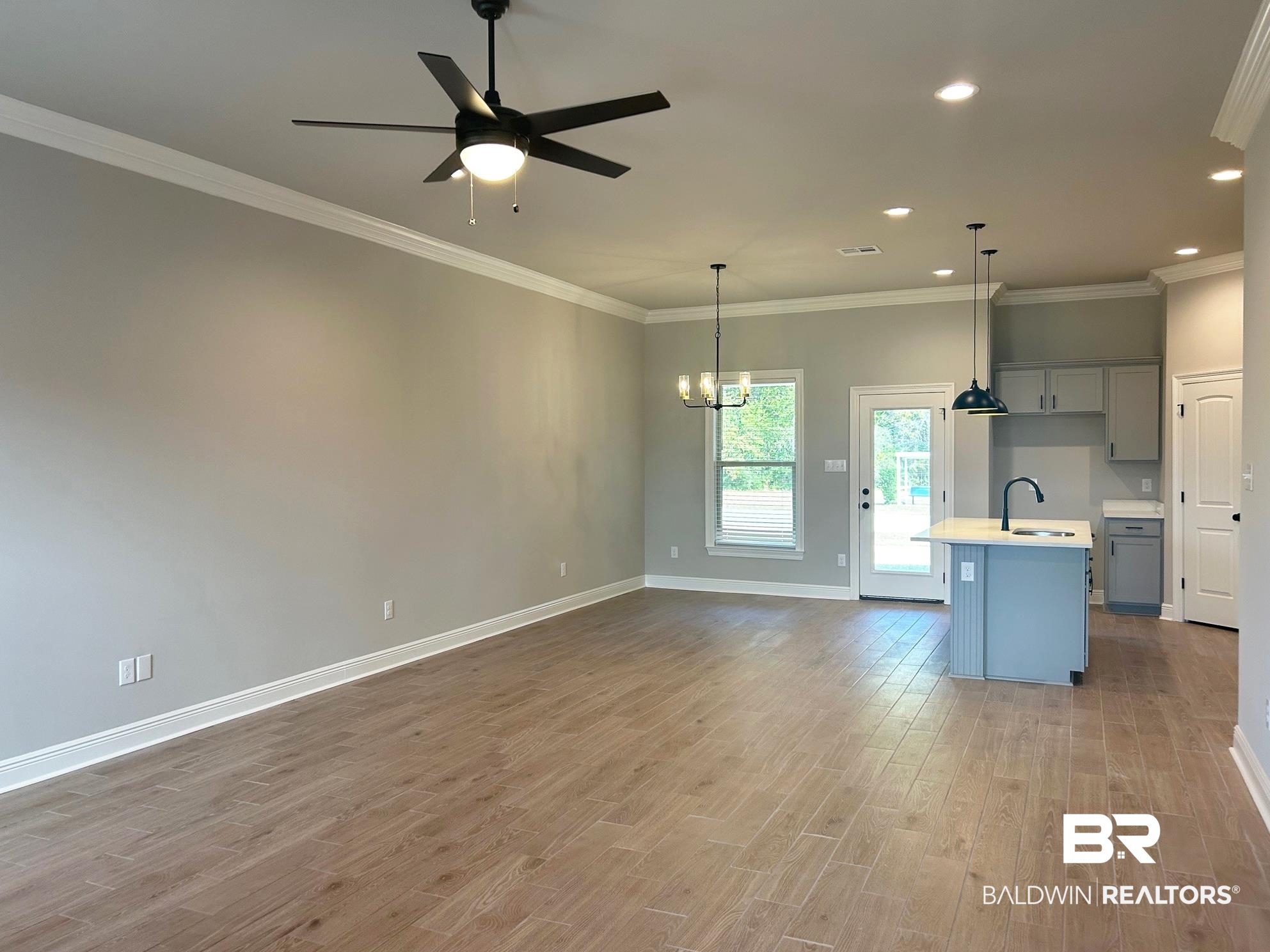808 Sumter Loop Foley, AL 36535 - Photo 6 of 18 Kitchen with wood-type flooring, a center island with sink, hanging light fixtures, and crown molding