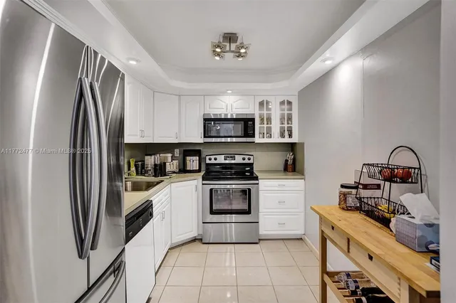 a kitchen with stainless steel appliances granite countertop white cabinets a sink a stove and dishwasher