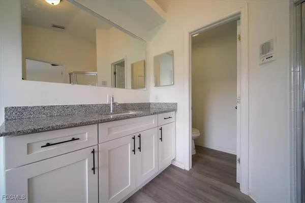 a bathroom with granite countertop a sink and a mirror