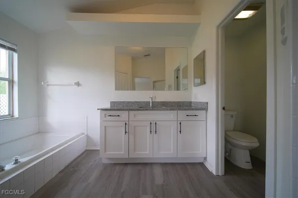 a bathroom with a granite countertop toilet sink and mirror