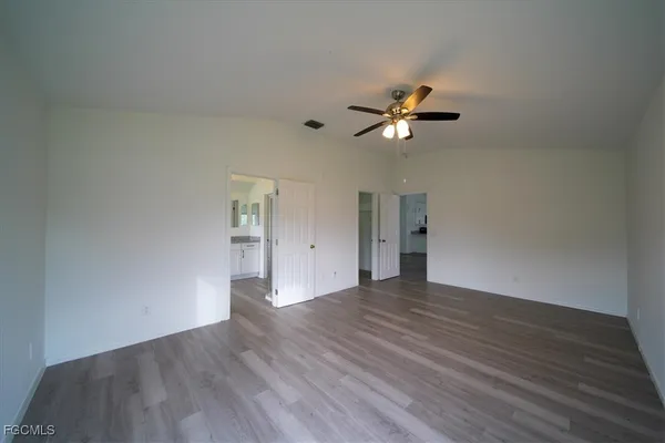 a view of empty room with wooden floor and fan