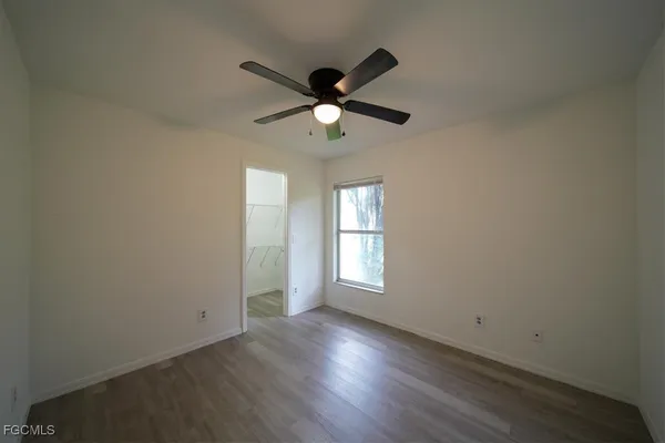 a view of empty room with wooden floor and fan