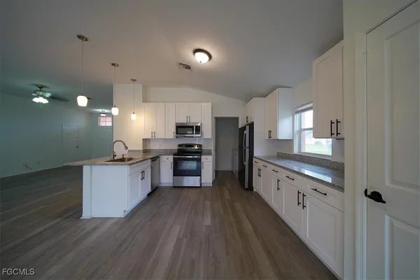 a large kitchen with a center island wooden floor stainless steel appliances and windows