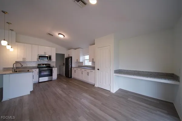 a kitchen with granite countertop a refrigerator and a stove top oven
