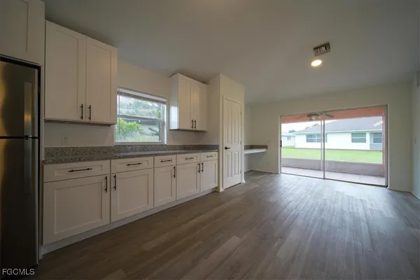a kitchen with a hard wood floor white cabinets and white appliances
