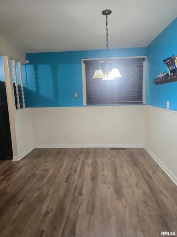 a view of a room with wooden floor and kitchen view