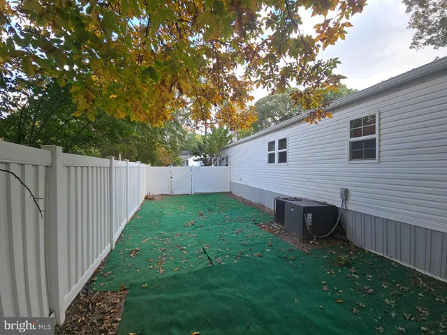 a view of a backyard with wooden fence and large trees