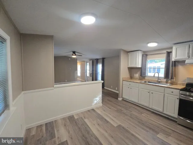 a large kitchen with kitchen island a sink dishwasher a stove and white countertops with wooden floor