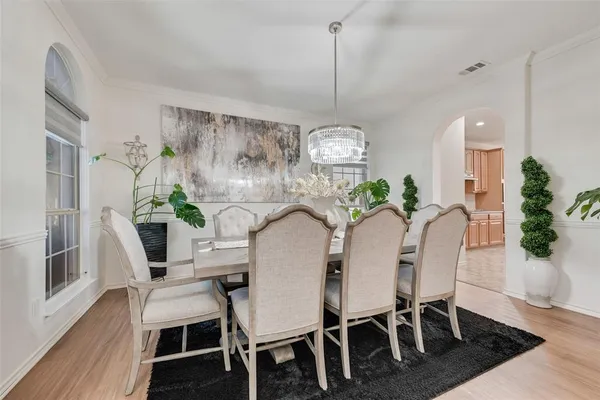 a view of a dining room with furniture a potted plant and wooden floor