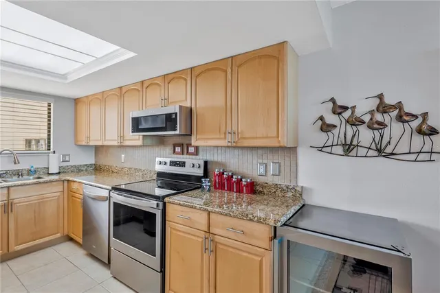 a kitchen with granite countertop stainless steel appliances sink stove and cabinets
