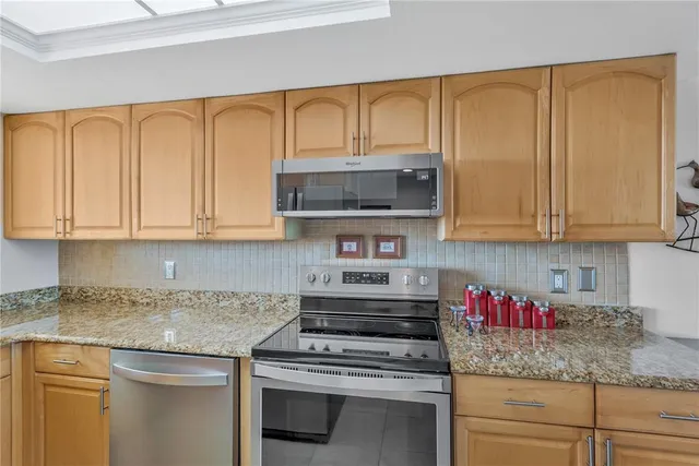 a kitchen with stainless steel appliances granite countertop white cabinets and a stove top oven