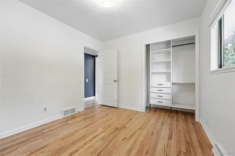 an empty room with wooden floor closet and windows