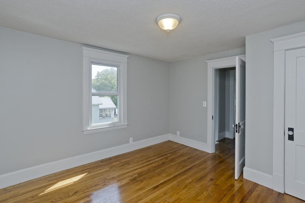 69 Merrimac Avenue Springfield, MA 01104 - Photo 22 of 42 an empty room with wooden floor and windows
