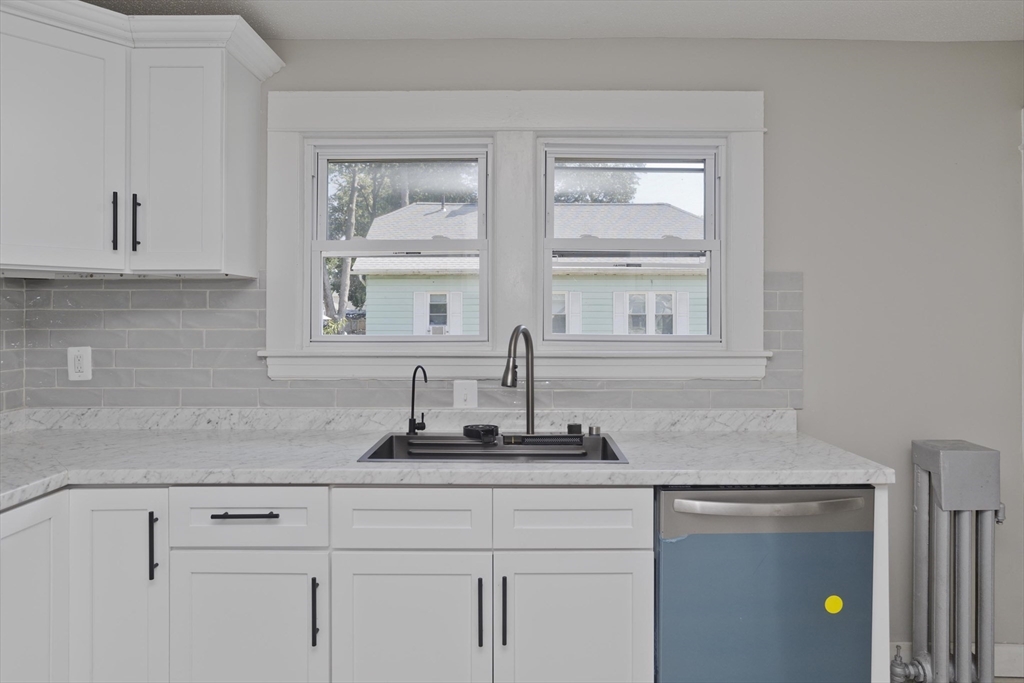 69 Merrimac Avenue Springfield, MA 01104 - Photo 3 of 42 a kitchen with a granite countertop white cabinets and a window