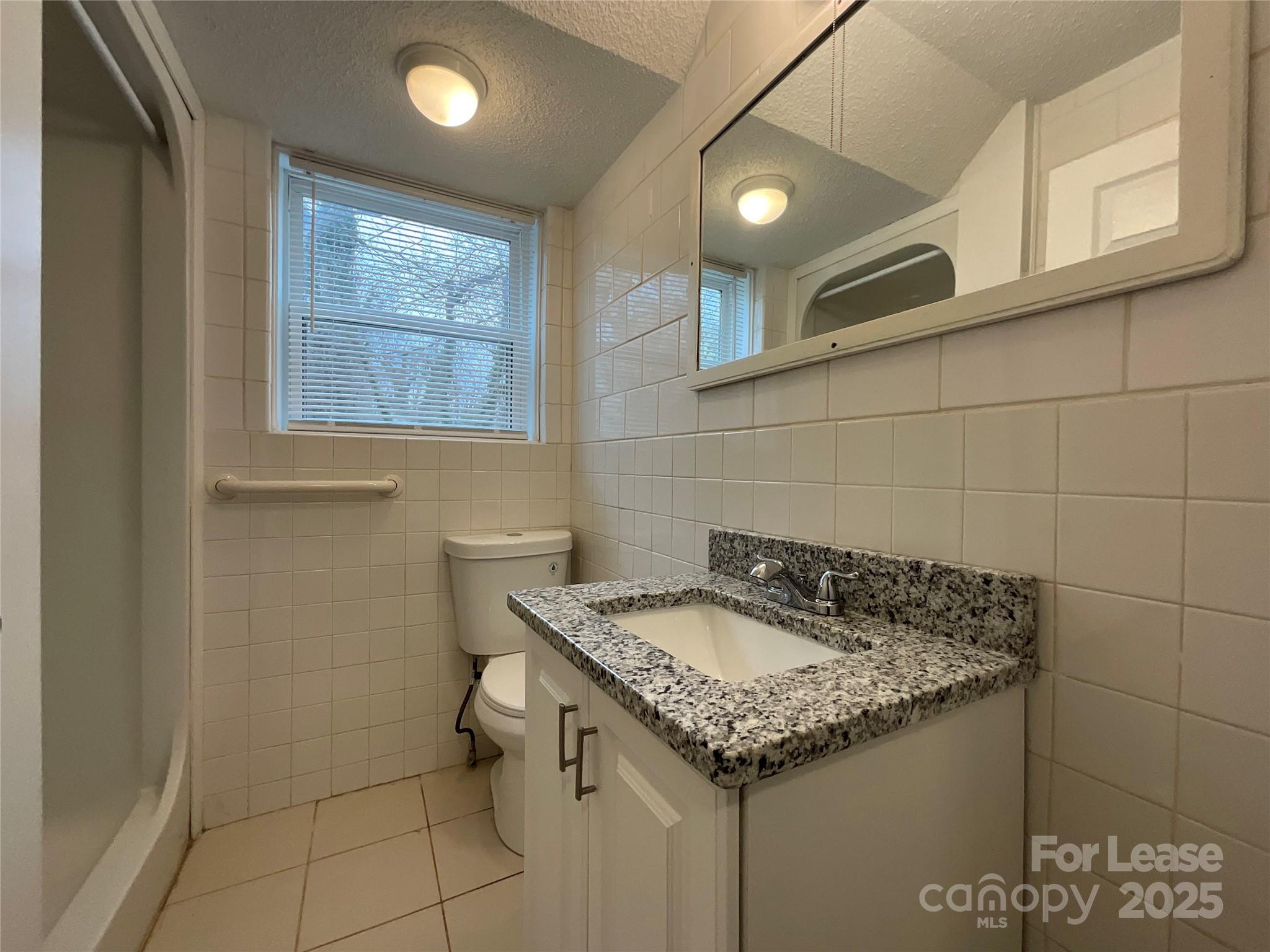 259 Jefferson Court Northeast, Unit 1 Concord, NC 28025 - Photo 7 of 9 a bathroom with a granite countertop sink and a toilet